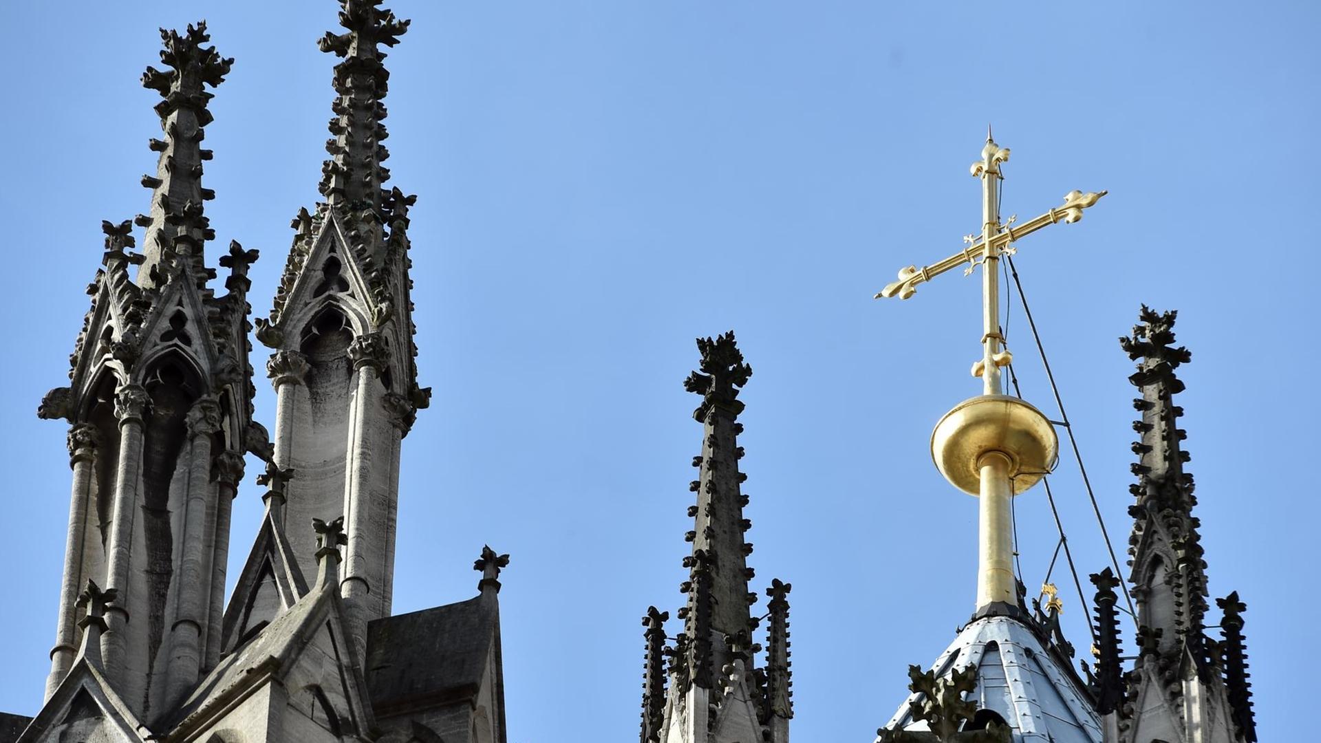 Ein goldenes Kreuz auf dem Kölner Dom leuchtet am 12.10.2017 in Köln (Nordrhein-Westfalen) in der Sonne. Ein goldenes Kreuz auf dem Kölner Dom leuchtet am 12.10.2017 in Köln (Nordrhein-Westfalen) in der Sonne.