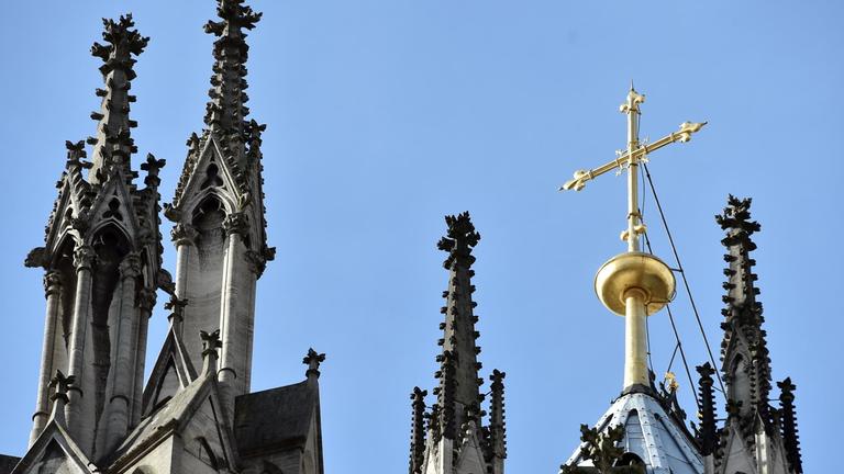 Ein goldenes Kreuz auf dem Kölner Dom leuchtet am 12.10.2017 in Köln (Nordrhein-Westfalen) in der Sonne. 