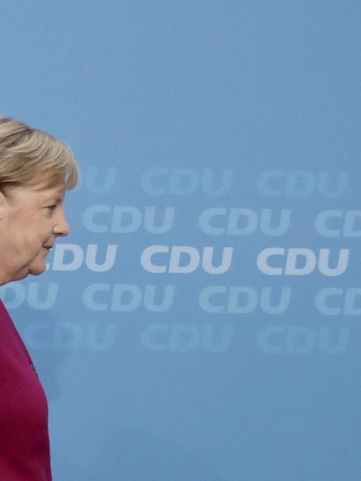 Kanzlerin Angela Merkel seitlich fotografiert vor einer blauen Wand, auf der das Wort "CDU" steht
