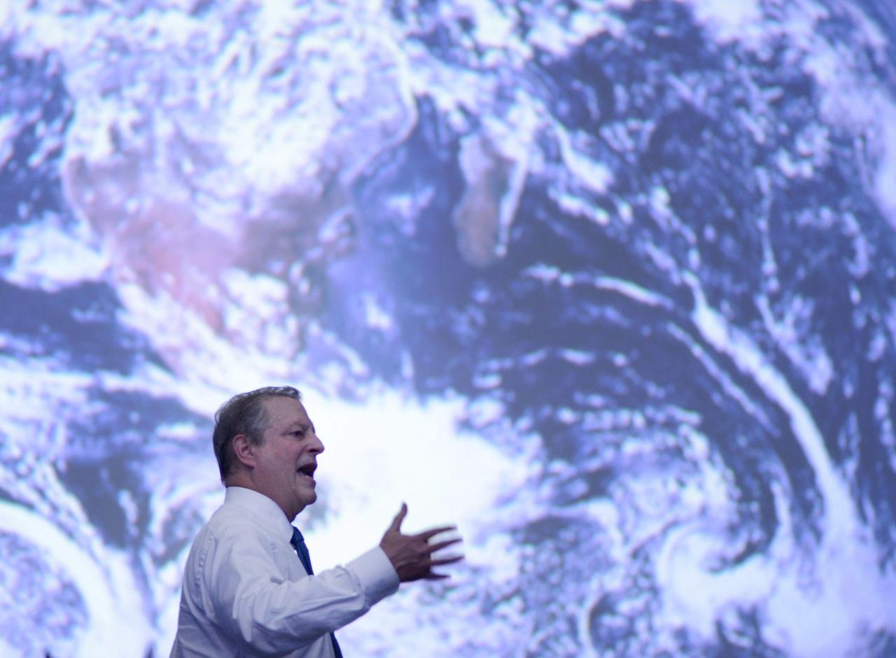Al Gore spricht auf der Klimakonferenz vor einem riesigen Satellitenbild der Erde.