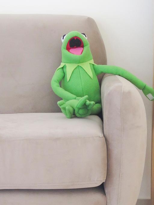 Kermit der Frosch sitzt auf einem Sofa.