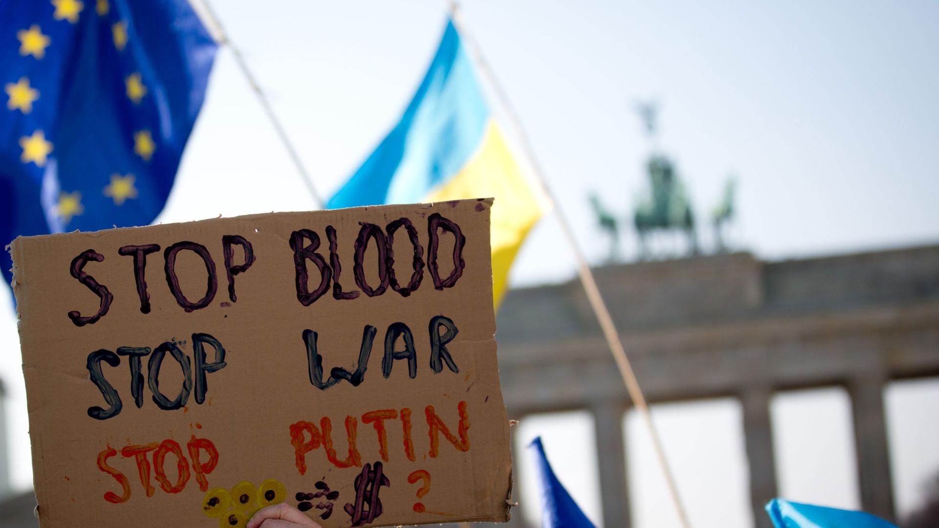 Im Rahmen einer Solidaritätsaktion für die Menschen in der Ukraine halten Menschen Plakate am Brandenburger Tor hoch. Im Rahmen einer Solidaritätsaktion für die Menschen in der Ukraine halten Menschen Plakate am Brandenburger Tor hoch.