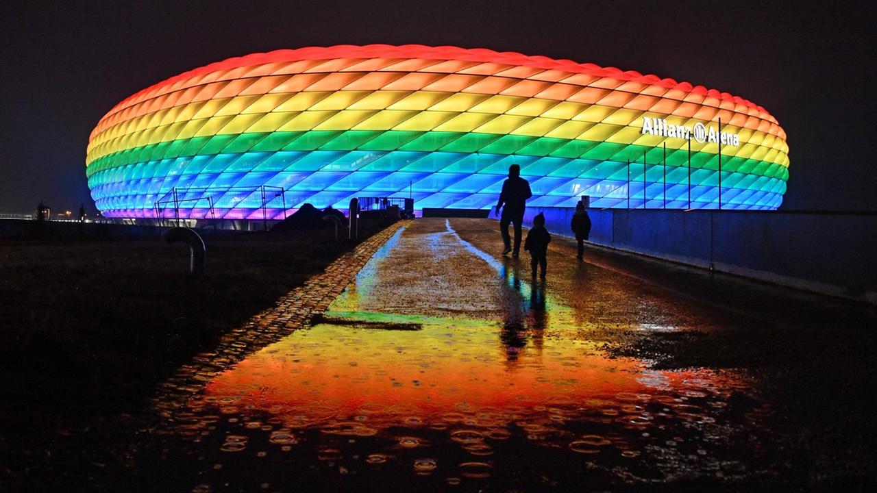 Die Allianz Arena in München leuchtet in der Nacht in Regenbogenfarben. Die Allianz Arena in München leuchtet in der Nacht in Regenbogenfarben.