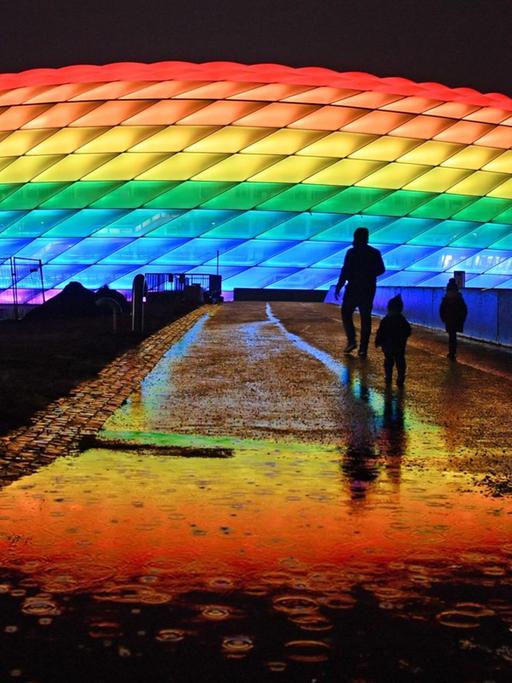 Die Allianz Arena in München leuchtet in der Nacht in Regenbogenfarben.