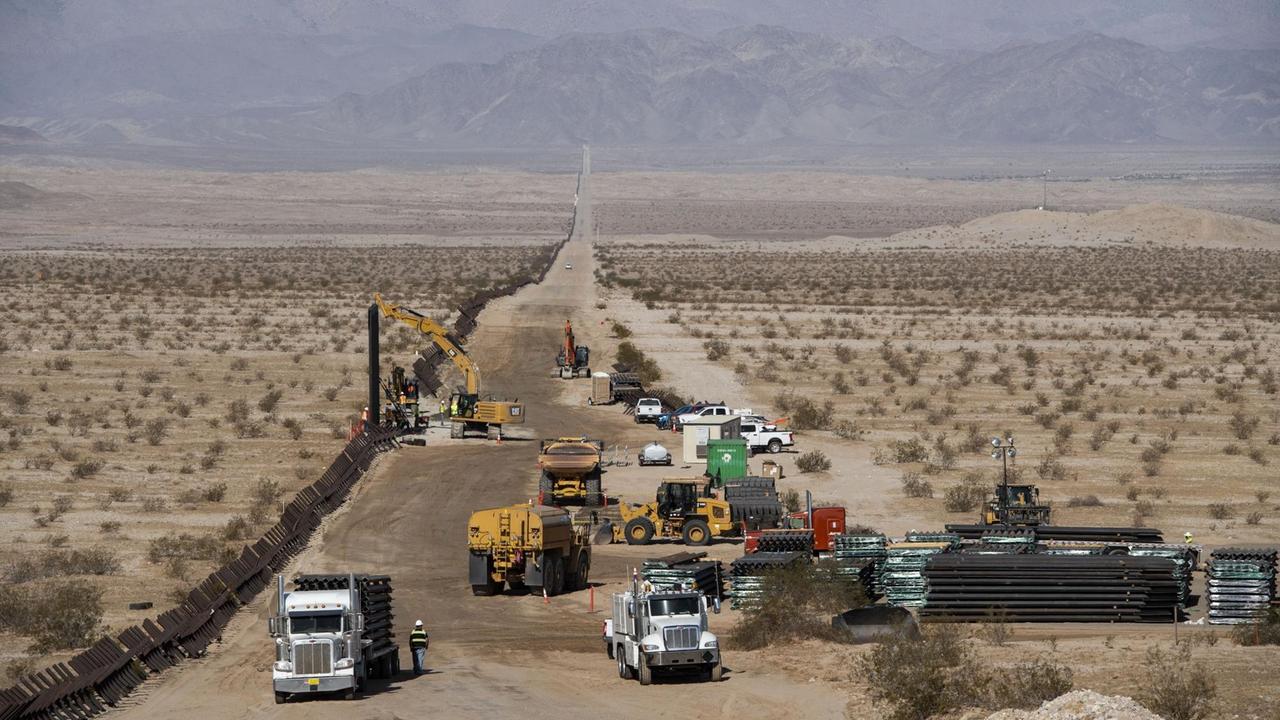Baufahrzeuge reissen den alten Grenzzaun entlang der US-amerikanischen Grenze zu Mexiko ab, am Straßenrand liegt das Baumaterial für die neue Grenzmauer.