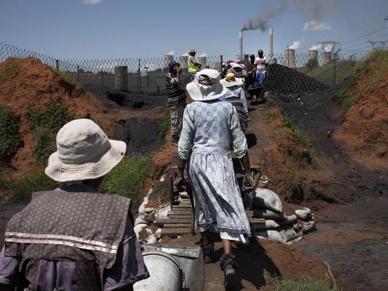 Frauen der Masakhane-Siedlung schieben Kohle-Schubkarren an einer Nahe gelegenen Miene in Emalahleni / Südafrika.