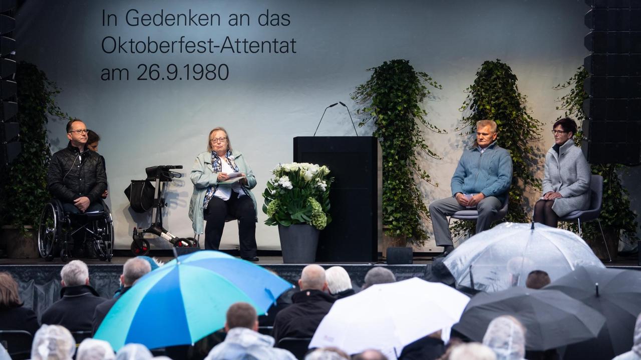 Dimitrios Lagkadinos, Renate Martinez, Robert Höckkmayr und Gudrun Lang sitzen bei einer Gedenkfeier nebeneinander auf der Bühne. Dimitrios Lagkadinos, Renate Martinez, Robert Höckkmayr und Gudrun Lang sitzen bei einer Gedenkfeier nebeneinander auf der Bühne.