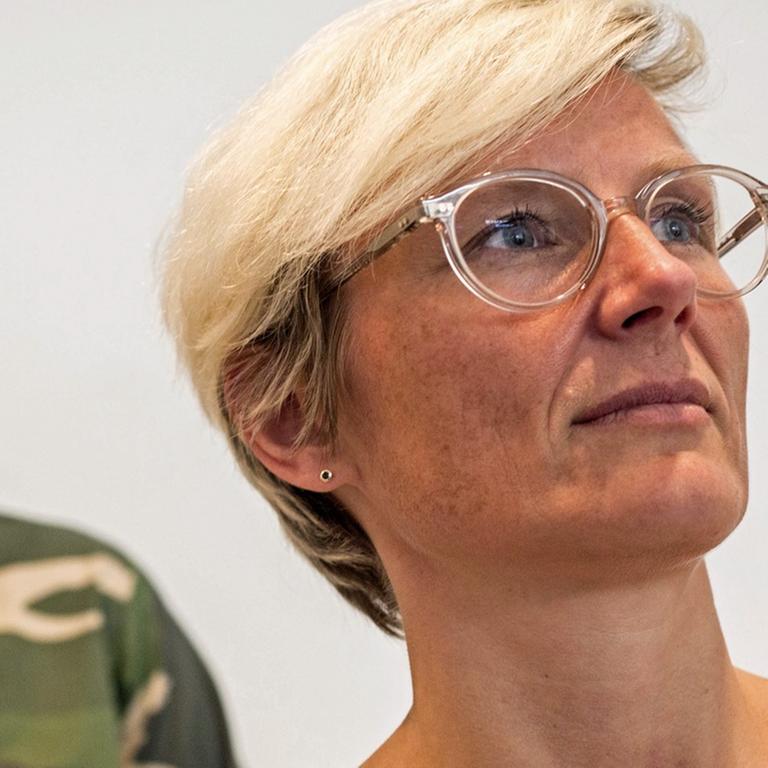 Ellen Blumenstein steht am 8.9.2016 in der von ihr kuratierten Ausstellung "Unter Waffen. Fire & Forget 2" im Museum für Angewandte Kunst in Frankfurt am Main vor einem Outfit des serbischen Modedesigners Sasa Kovacevic (l).