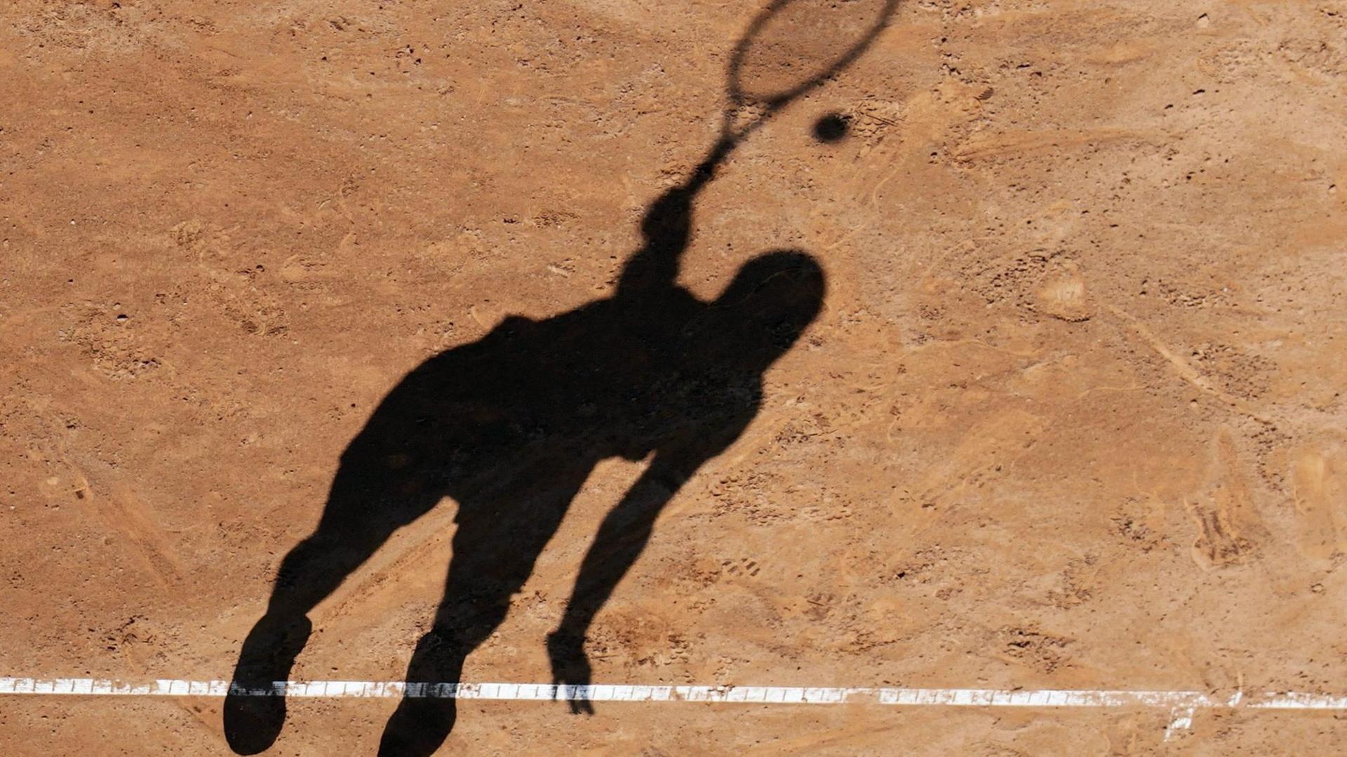 Der Schatten eines Tennisspielers beim Aufschlag auf einem Sandplatz. Der Schatten eines Tennisspielers beim Aufschlag auf einem Sandplatz.