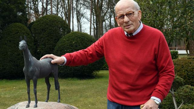 Der ehemalige Springreiter Hans Günter Winkler posiert am 16.03.2016 im Garten seines Hauses in Warendorf (Nordrhein-Westfalen) neben der Bronzestatue seiner «Wunderstute» Halla, die auf einem Findling steht.