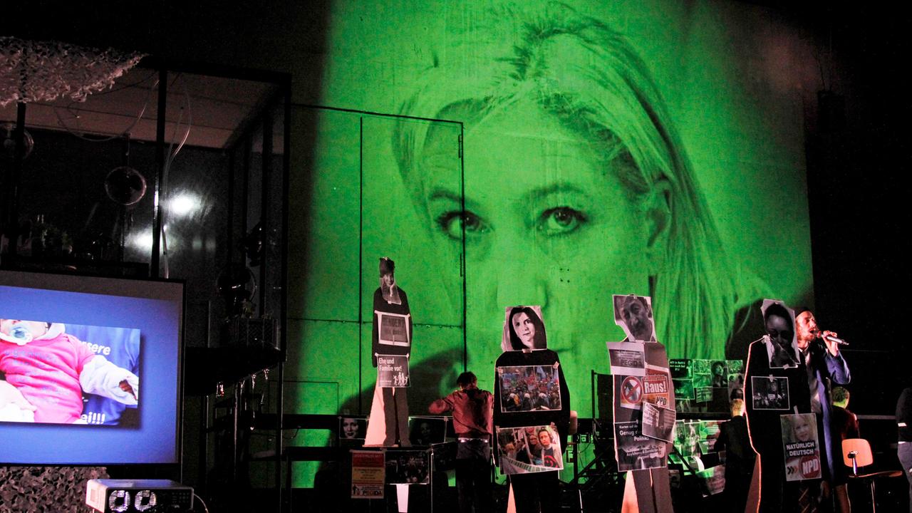 Eine Szene aus dem Stück "Fear" von Falk Richter, aufgeführt an der Berliner Schaubühne – im Hintergrund ist in einer Videoprojektion Marine Le Pen, Parteivorsitzende der französischen Front National, zu sehen. Eine Szene aus dem Stück "Fear" von Falk Richter, aufgeführt an der Berliner Schaubühne – im Hintergrund ist in einer Videoprojektion Marine Le Pen, Parteivorsitzende der französischen Front National, zu sehen.