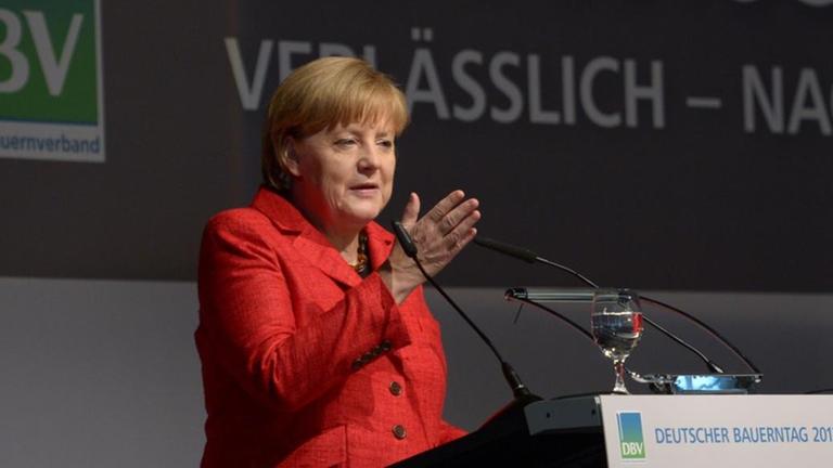 Angela Merkel auf dem Bauerntag 2013 am Rednerpult. Hinter ihr das Logo des Verbandes.
