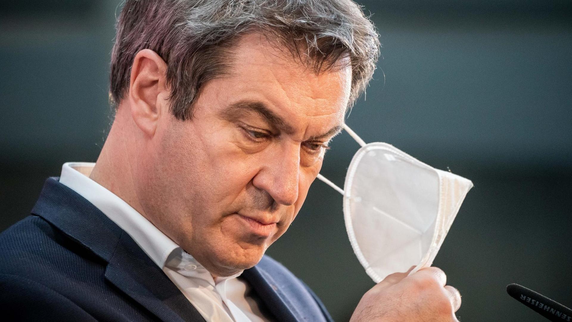 Markus Söder nimmt seine Maske bei einer Pressekonferenz ab. Markus Söder nimmt seine Maske bei einer Pressekonferenz ab.