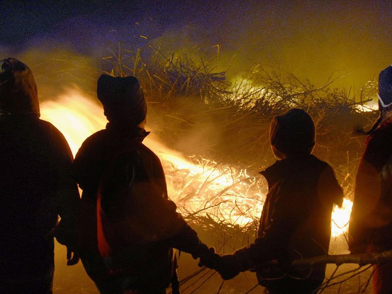 Kinder stehen in Eiderstedt vor einem Biikefeuer.