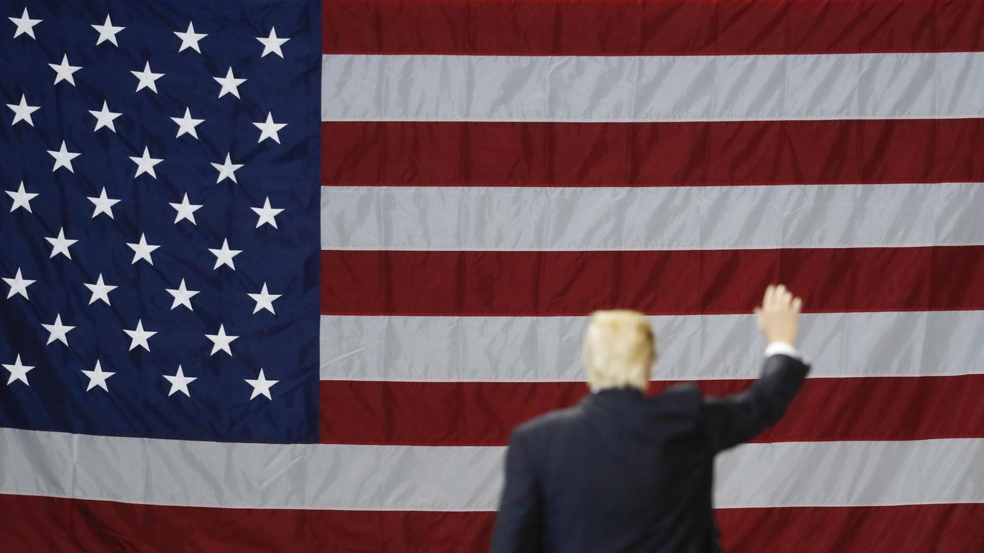 US-Präsident Donald Trump von hinten vor einer US-Flagge US-Präsident Donald Trump von hinten vor einer US-Flagge