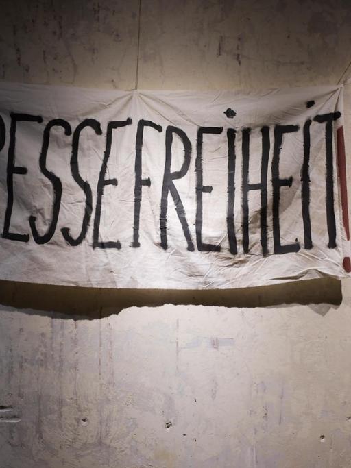 Ein Transparent mit der Aufschrift "Pressefreiheit" hängt an einer Wand.