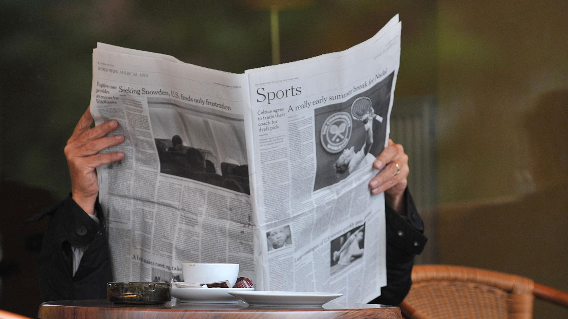Ein Mann sitzt in einem Cafe und liest eine Zeitung. Ein Mann sitzt in einem Cafe und liest eine Zeitung.