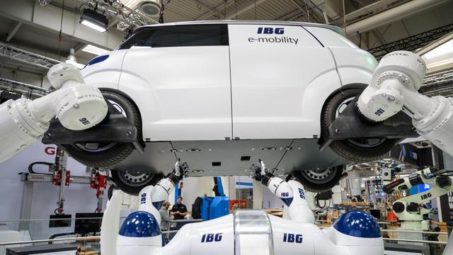 Das Foto zeigt den Stand des Herstellers IBG auf der Hannover Messe. Dort werden Roboter gezeigt, die an einem Automodell arbeiten.
