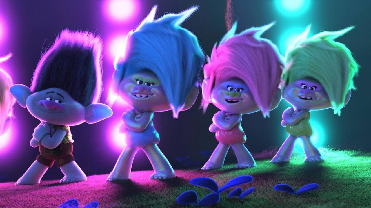 Filmszene aus "Trolls World Tour": Auf einer Bühne stehen Troll-Animationsfigürchen in vor violetten und grünen Scheinwerfern. Filmszene aus "Trolls World Tour": Auf einer Bühne stehen Troll-Animationsfigürchen in vor violetten und grünen Scheinwerfern.