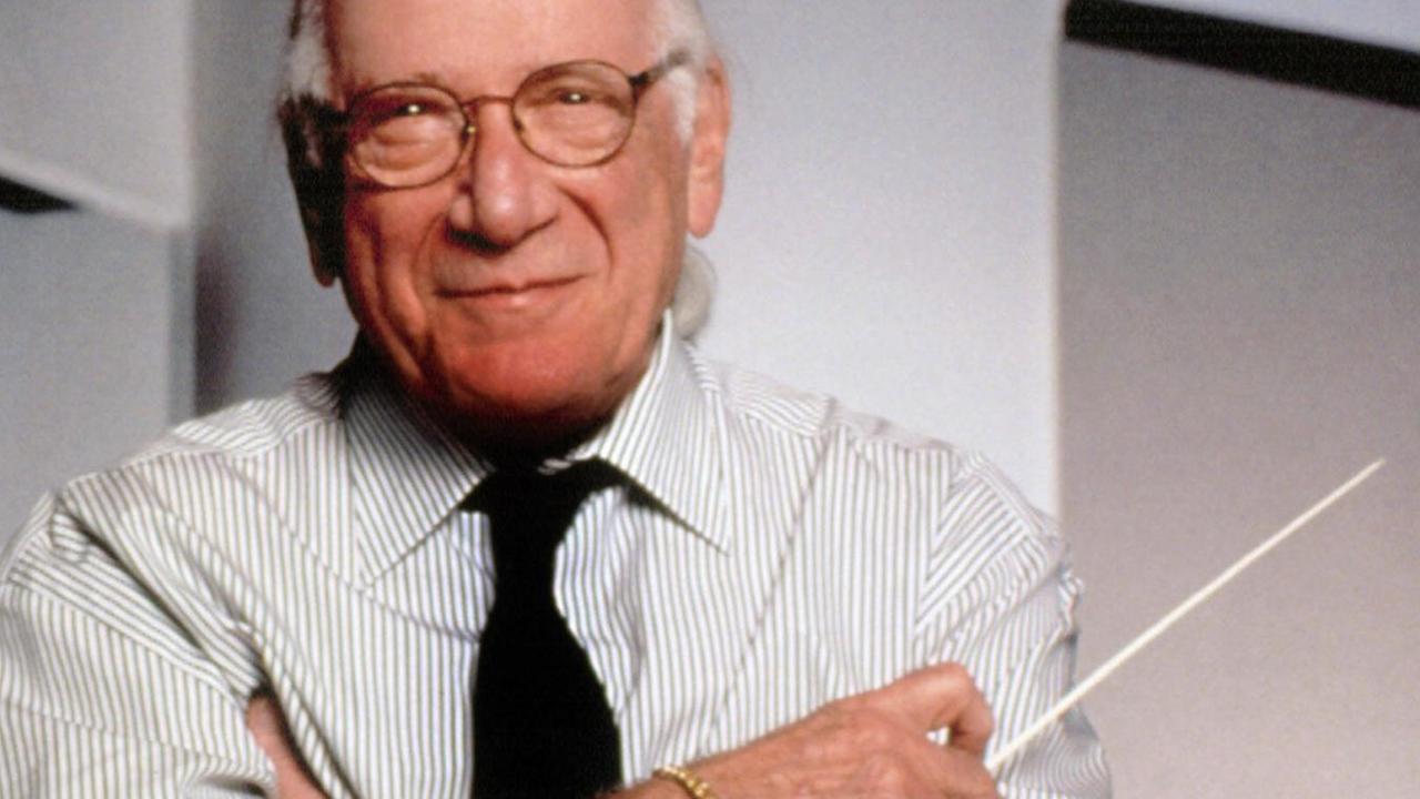 Jerry Goldsmith steht mit dem Taktstock in der Hand und blickt in die Kamera. Jerry Goldsmith steht mit dem Taktstock in der Hand und blickt in die Kamera.