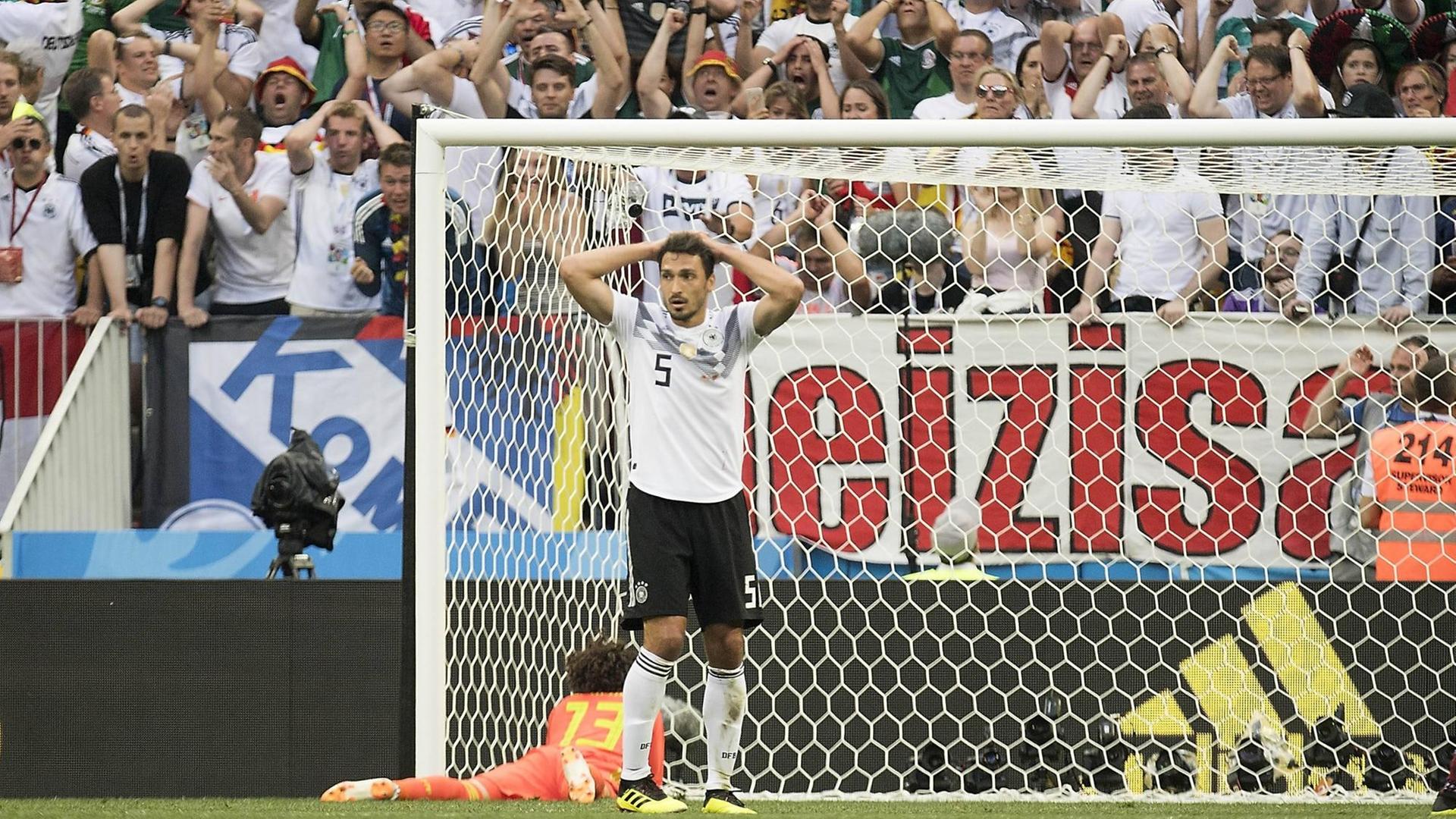Mats Hummels ist nach einer vergebenen Torchance im ersten Vorrundenspiel gegen Mexiko enttäuscht. Auch die deutschen Fans im Hintergrund sind entsetzt.