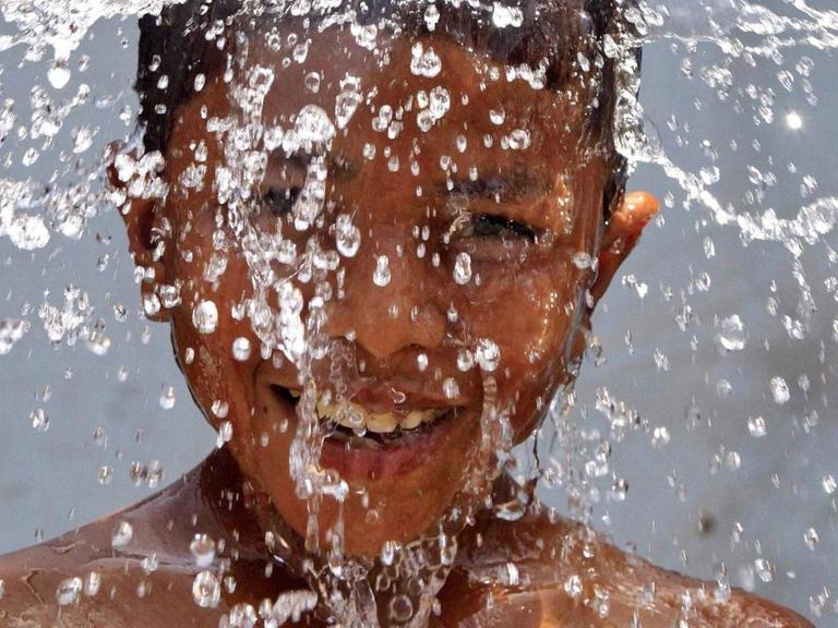 Ein Junge genießt die Abkühlung beim Duschen (2010)