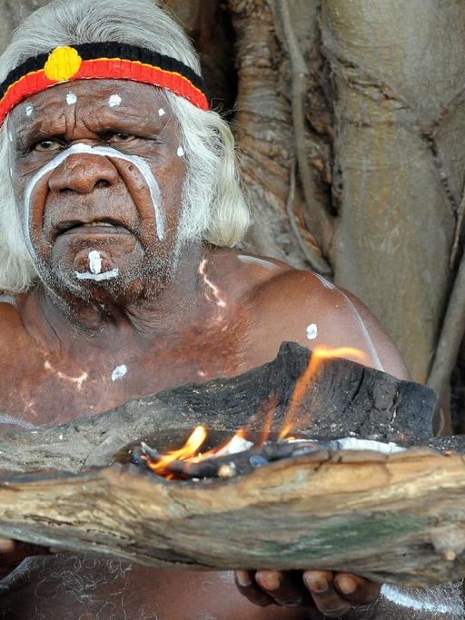 Ein älterer Aborigine bei einer Willkommens-Zeremonie auf Goat-Island ind Australien. Er hält eine Schale mit Feuer in der Hand.