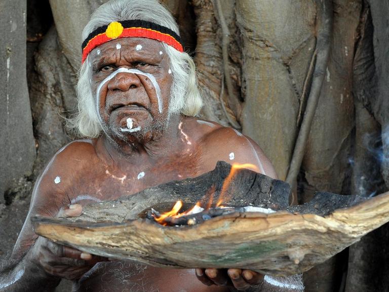 Ein älterer Aborigine bei einer Willkommens-Zeremonie auf Goat-Island ind Australien. Er hält eine Schale mit Feuer in der Hand.
