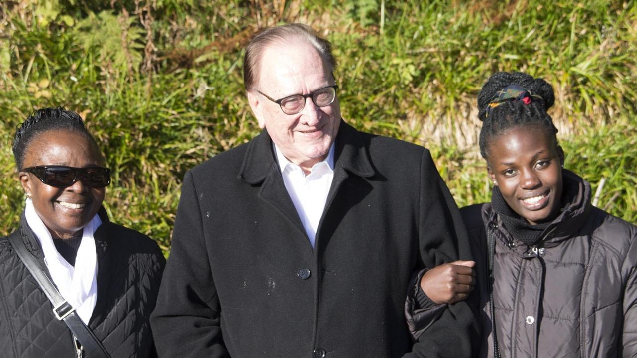 Die Kenianierin Asuna, ihr Mann Willy und eine Nichte Asunas stehen untergehakt da. Die Kenianierin Asuna, ihr Mann Willy und eine Nichte Asunas stehen untergehakt da.