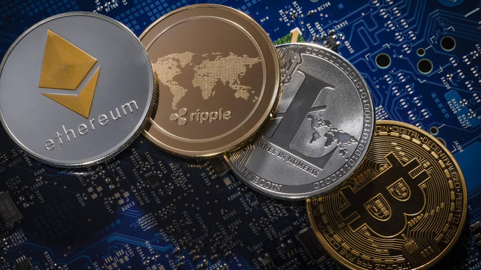 Münzen der Kryptowährungen Ethereum, ripple, Litecoin und Bitcoin liegen auf der Platine eines Computers Münzen der Kryptowährungen Ethereum, ripple, Litecoin und Bitcoin liegen auf der Platine eines Computers