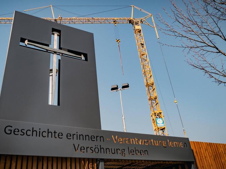 Vor einem Baukran an der Baustelle für den Wiederaufbau der Garnisonkirche in Potsdam ist ein stilisiertes christliches Kreuz zu sehen. Die Botschaft darunter lautet: Geschichte erinnern - Verantwortung lernen - Versöhnung leben