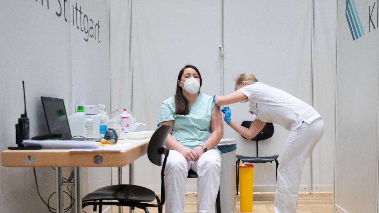 Christine Helbig (l), Pflegekraft am Klinikum Stuttgart wird im Impfzentrum des Klinikum Stuttgart von einer Ärztin mit einer Dosis eines Covid-19 Impfstoffes geimpft. Helbig hatte am vormittag Dienst in einer Covid-19 Station des Klinikum Stuttgart und kam direkt von der Arbeit zur Impfung. Sie ist eine der ersten Menschen in Baden-Württemberg, die geimpft wurden. Am Sonntag haben die Corona-Impfungen mit dem Impfstoff von Biontech/Pfizer in Deutschland begonnen. Christine Helbig (l), Pflegekraft am Klinikum Stuttgart wird im Impfzentrum des Klinikum Stuttgart von einer Ärztin mit einer Dosis eines Covid-19 Impfstoffes geimpft. Helbig hatte am vormittag Dienst in einer Covid-19 Station des Klinikum Stuttgart und kam direkt von der Arbeit zur Impfung. Sie ist eine der ersten Menschen in Baden-Württemberg, die geimpft wurden. Am Sonntag haben die Corona-Impfungen mit dem Impfstoff von Biontech/Pfizer in Deutschland begonnen.