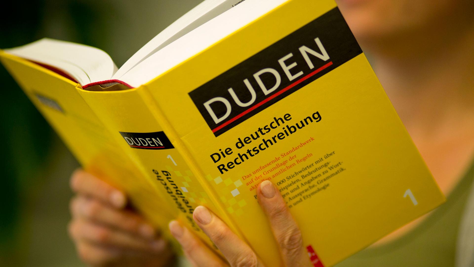 Eine Frau liest im Duden. Eine Frau liest im Duden.