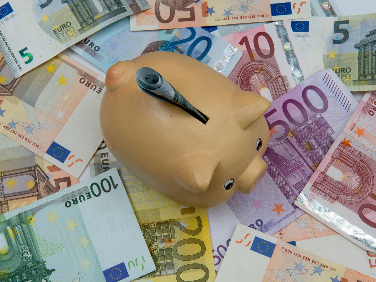 Ein Sparschwein steht auf verschiedenen Euro-Banknoten. Ein Sparschwein steht auf verschiedenen Euro-Banknoten.