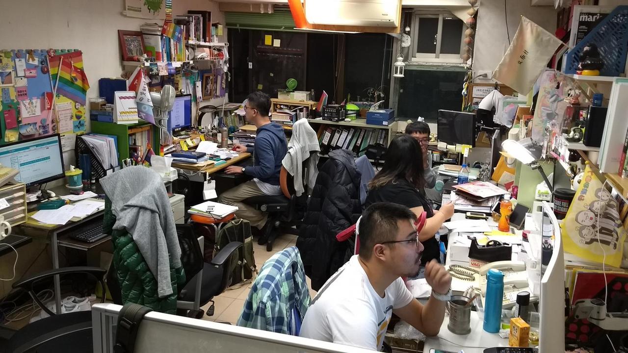 Die Mitarbeiter der Tongzhi-Hotline für LGBT-Fragen in Taiwan sitzten in einem kleinen Büro mit vielen Rechnern, Büchern und Dokumenten.