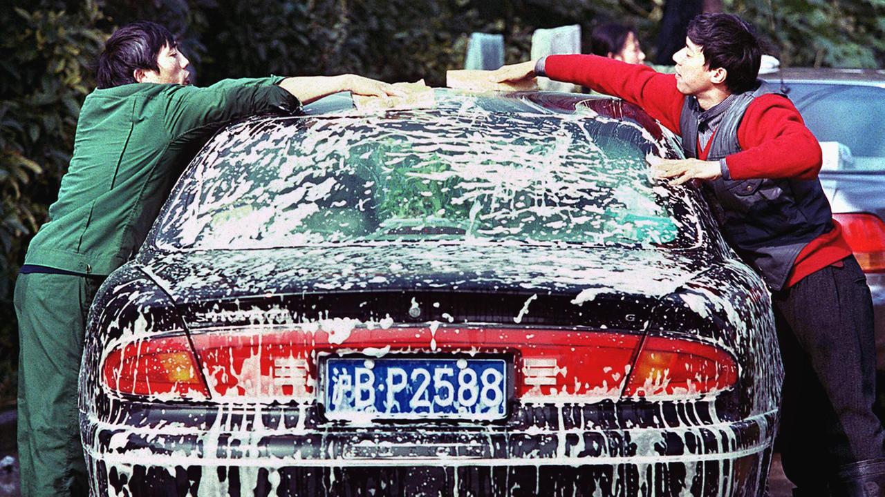 Zwei Arbeiter waschen ein Auto in Schanghai.