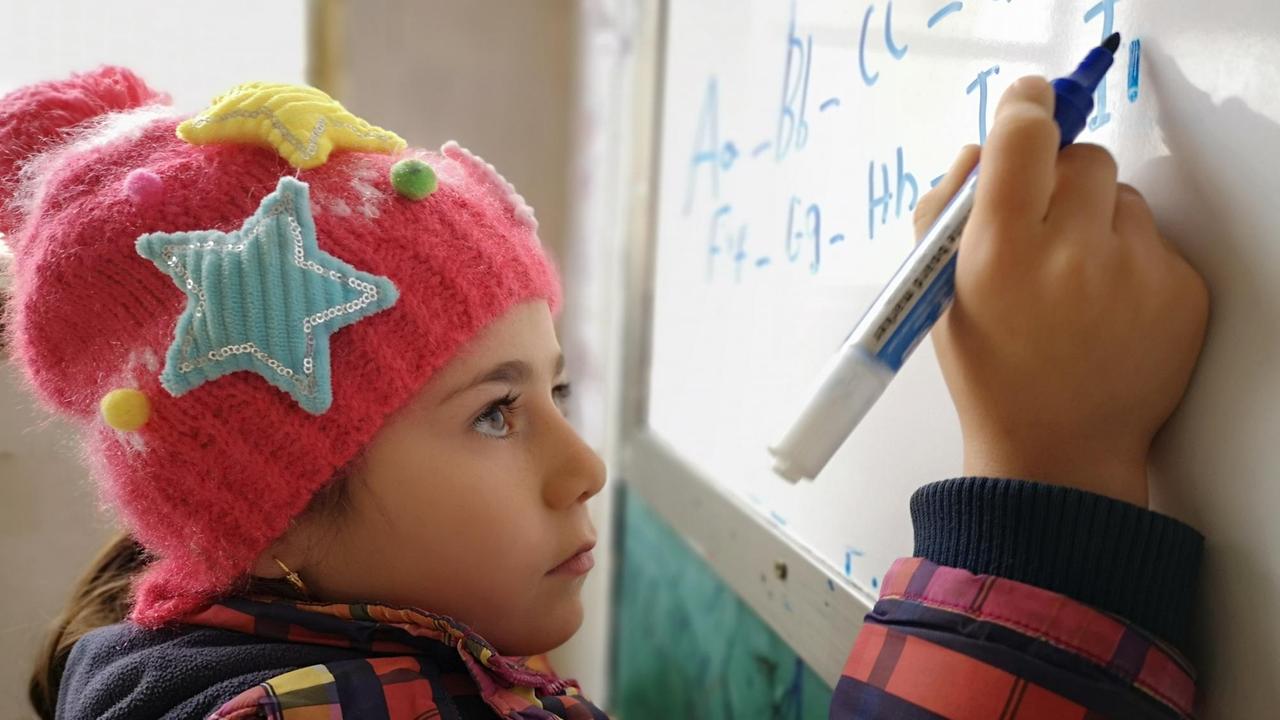 Mädchen an der Tafel übt kurdisches Alphabet