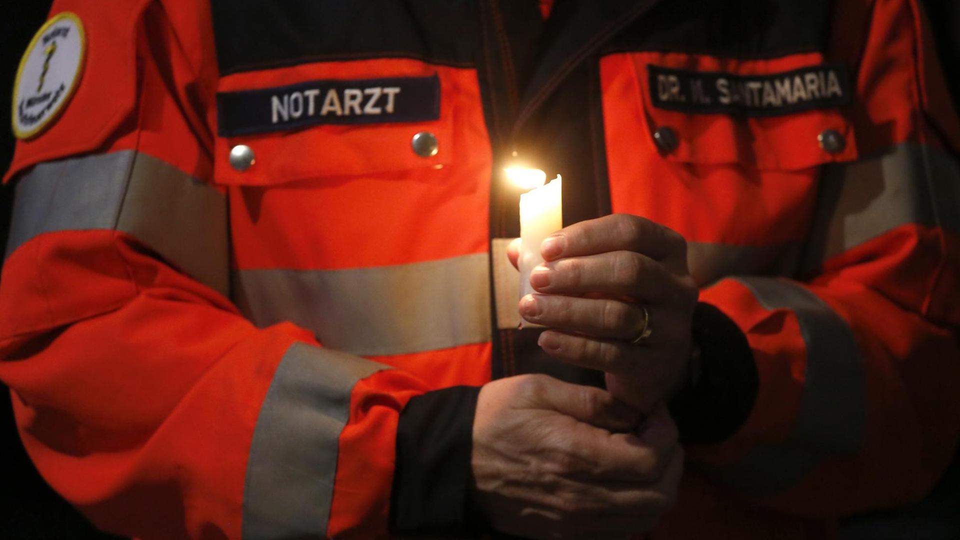 Ein Notarzt hält bei einem ökumenischen Gottesdienst im Dom in Münster eine Kerze zum Gedenken an die Opfer.