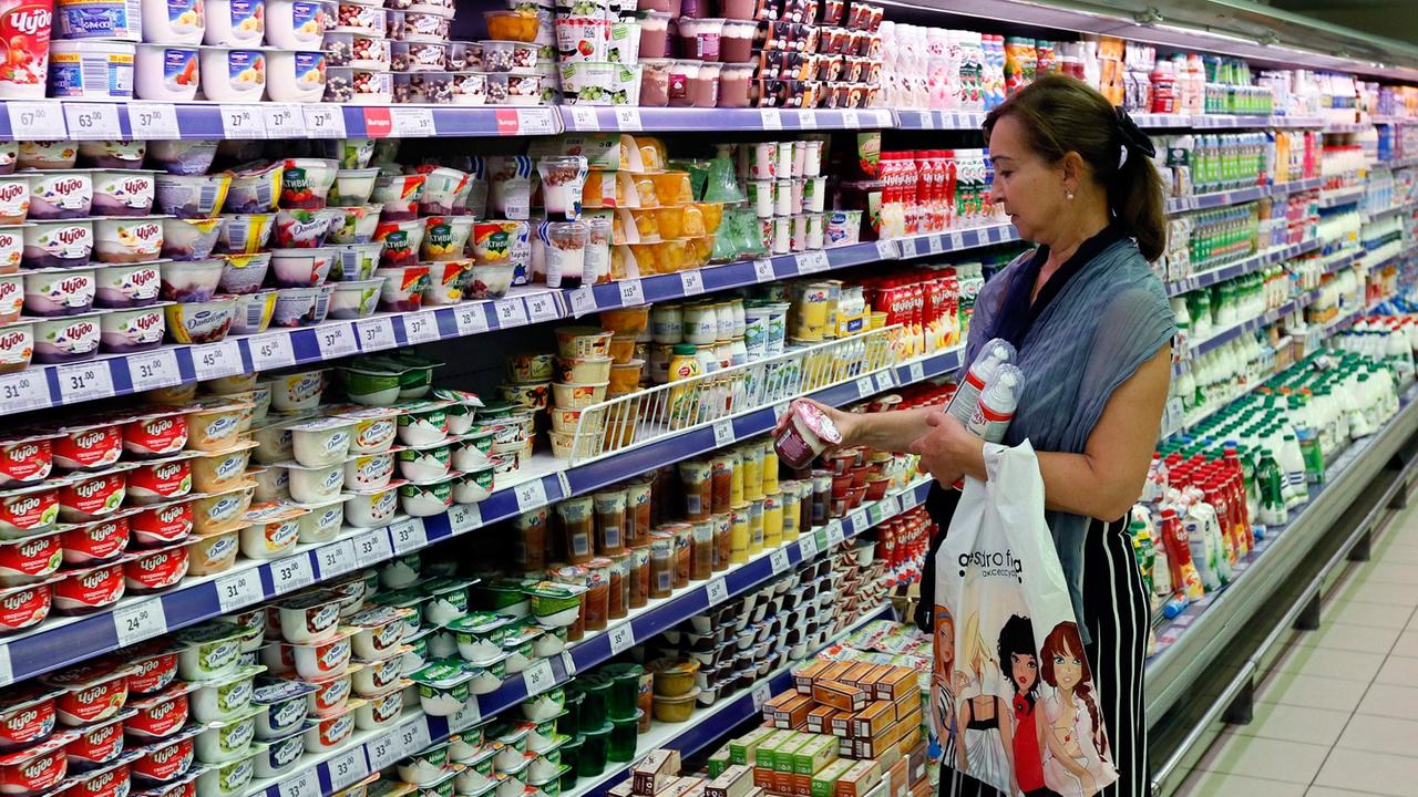 Eine Frau steht in einem Moskauer Supermarkt vor einer Kühltheke mit Milchprodukten. Eine Frau steht in einem Moskauer Supermarkt vor einer Kühltheke mit Milchprodukten.