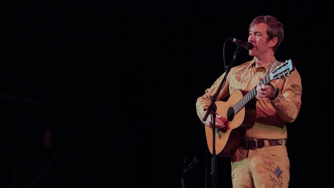 Bill Callahan mit Akustikgitarre auf einer Bühne Bill Callahan mit Akustikgitarre auf einer Bühne
