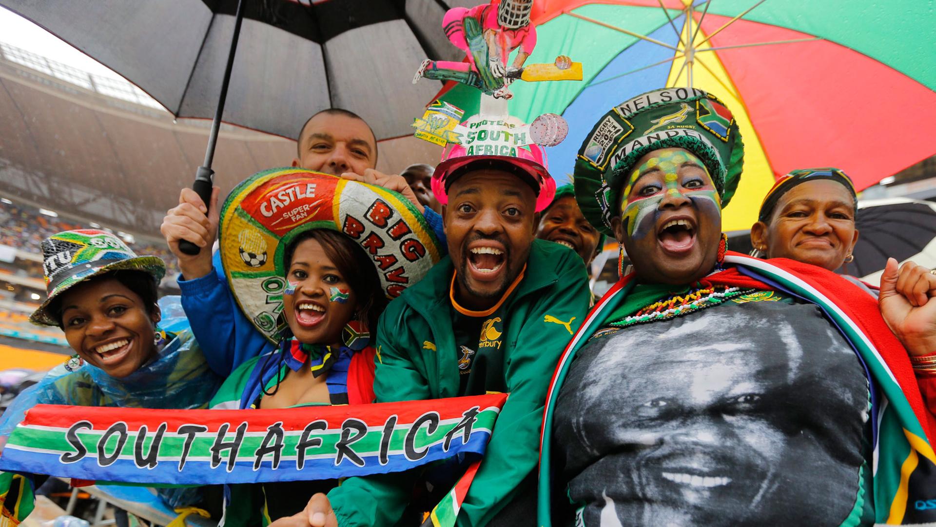 Eine Gruppe von Menschen bei der Trauerfeier für Nelson Mandela, eine Frau trägt ein T-Shirt mit seinem Konterfei Eine Gruppe von Menschen bei der Trauerfeier für Nelson Mandela, eine Frau trägt ein T-Shirt mit seinem Konterfei