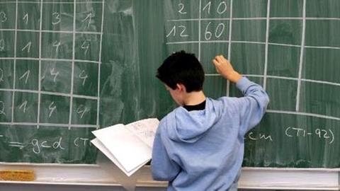 Ein Schüler einer 7. Klasse schreibt während einer Mathematik-Stunde Rechenergebnisse an die Tafel