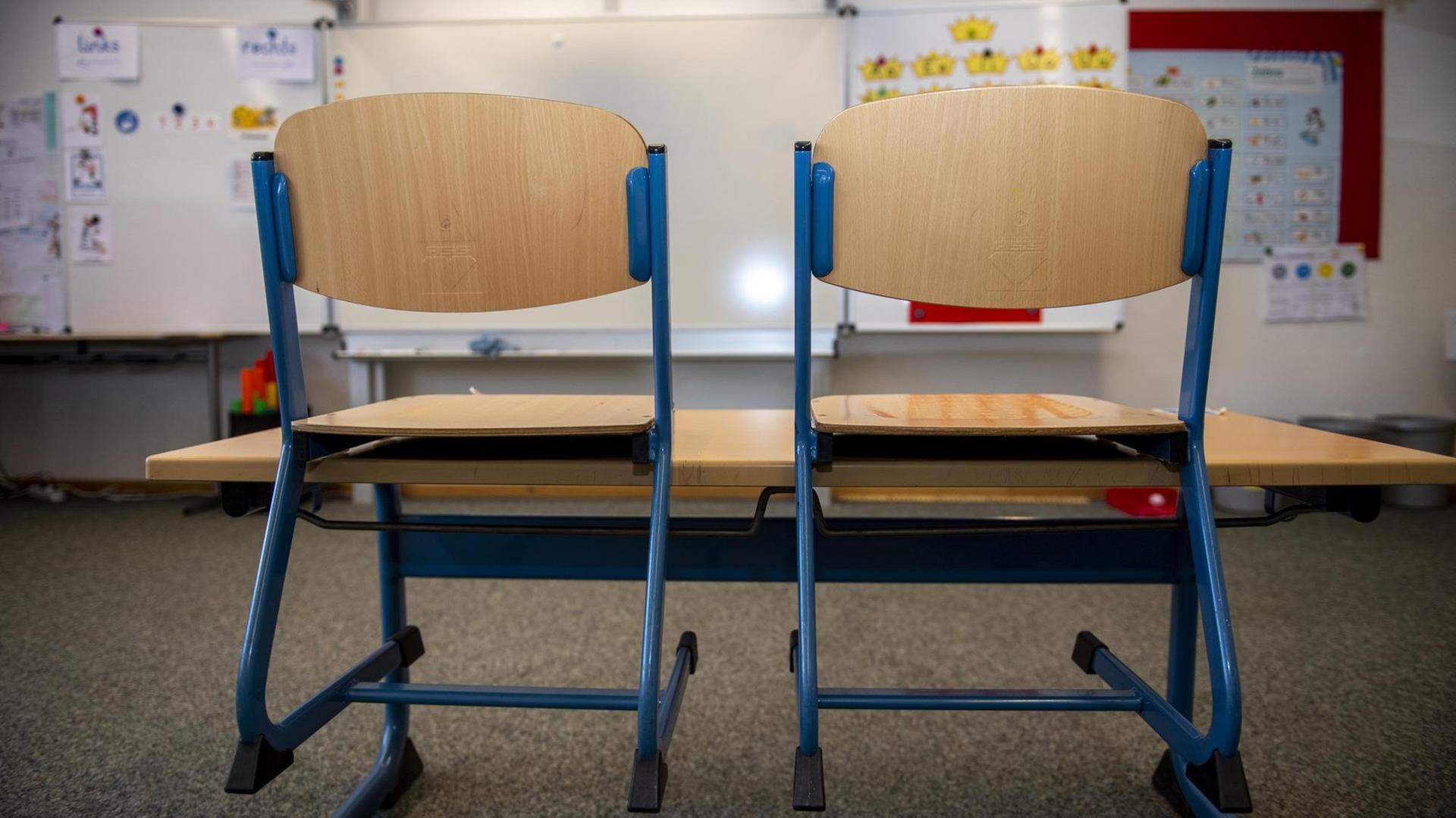 In einem leeren Klassenraum einer Grundschule sind die Stühle auf die Bänke gestellt In einem leeren Klassenraum einer Grundschule sind die Stühle auf die Bänke gestellt
