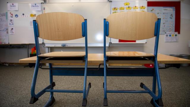 In einem leeren Klassenraum einer Grundschule sind die Stühle auf die Bänke gestellt