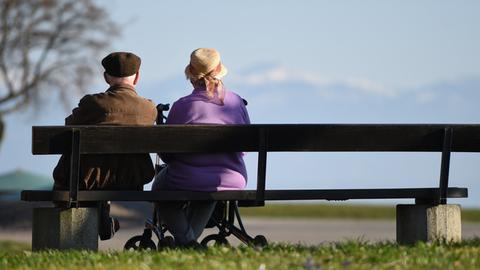 Zwei Senioren sitzen an der Uferpromenade in Langenargen (Baden-Württemberg) auf einer Parkbank.