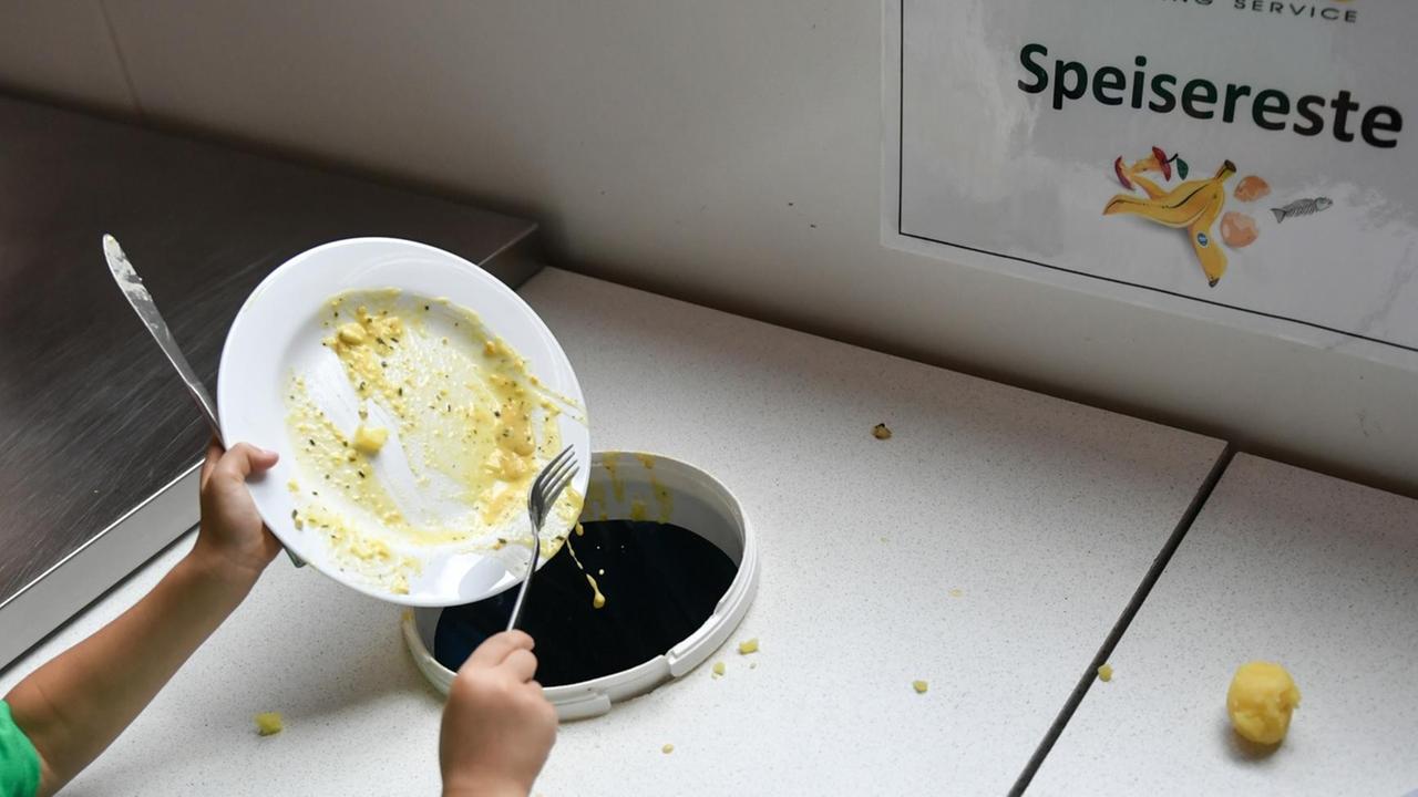Ein Schüler wirft nach dem Mittagessen Essensreste in bereitgestellte Behälter Ein Schüler wirft nach dem Mittagessen Essensreste in bereitgestellte Behälter