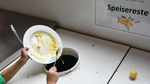 Ein Schüler wirft nach dem Mittagessen Essensreste in bereitgestellte Behälter