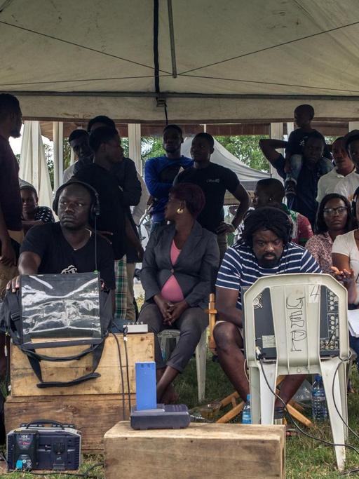 Eine nigeriansche Filmcrew steht zusammen unter einem Zelt.
