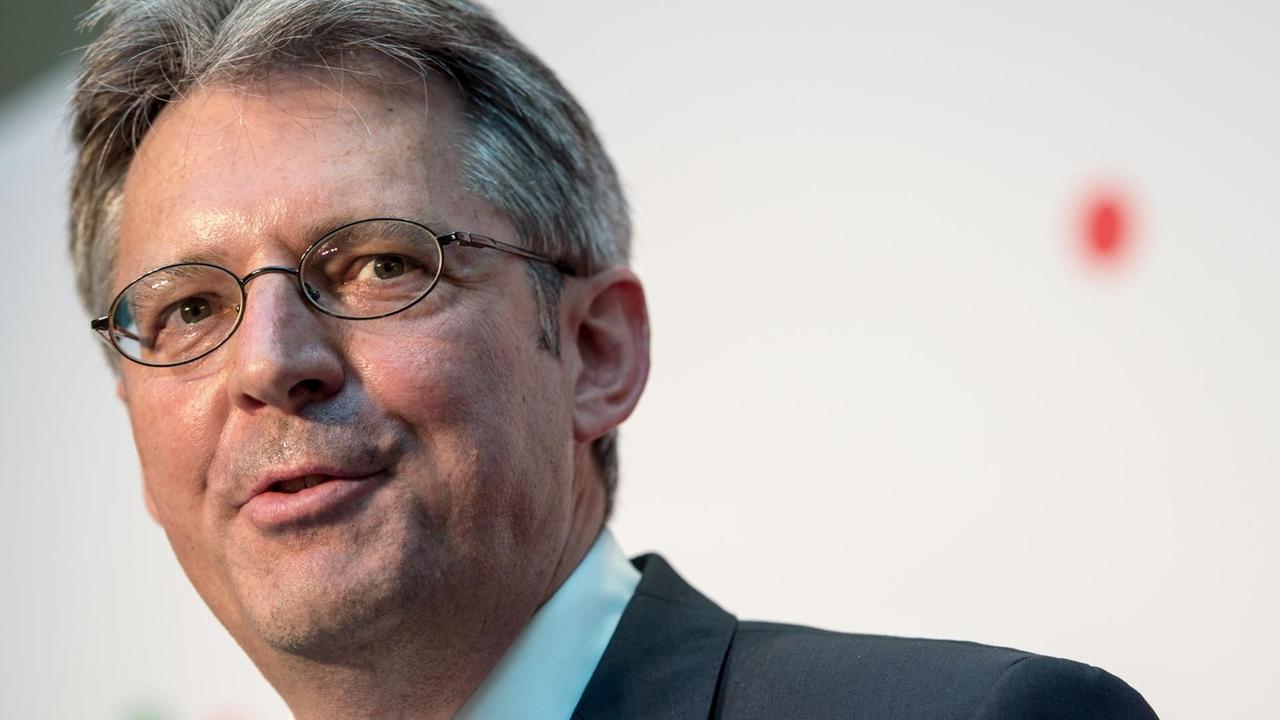 Post steht lächelnd vor einer weißen Wand und scheint mit jemandem zu sprechen. Post steht lächelnd vor einer weißen Wand und scheint mit jemandem zu sprechen.