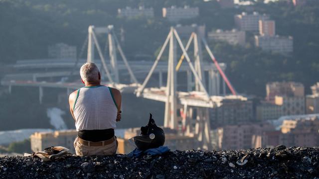 Ein Mann blickt am 28.06.2019 auf die Überreste der zerstörten Morandi-Brücke in Genua, kurz vor ihrer kontrollierten Sprengung.